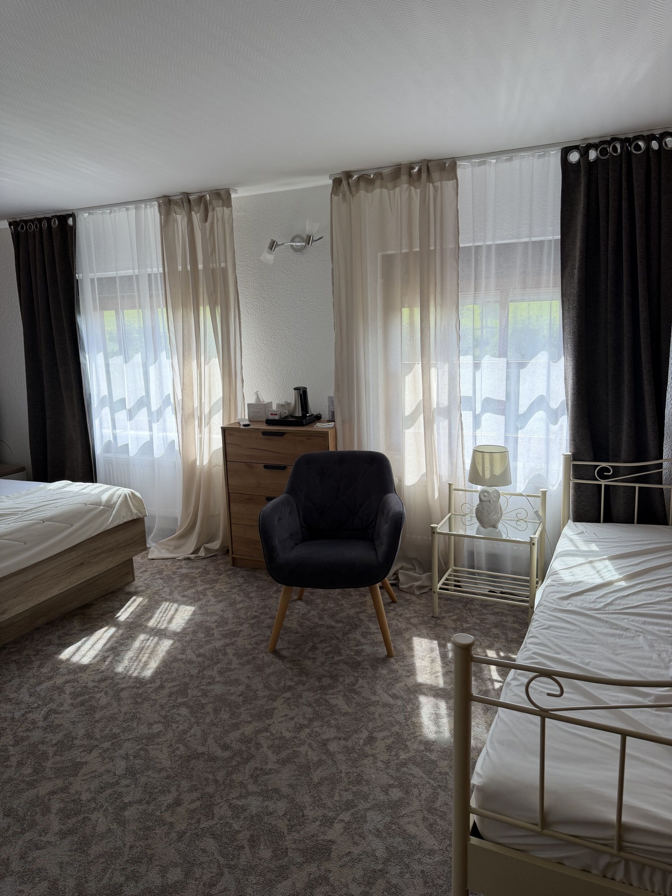 A bedroom with two beds, a wooden dresser, a chair, and a lamp.
