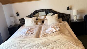 A neatly made bed with a quilted headboard, a bedside table with a lamp, and a wall-mounted light fixture.