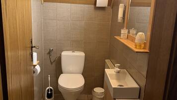 A compact bathroom with a toilet, sink, and storage shelves.