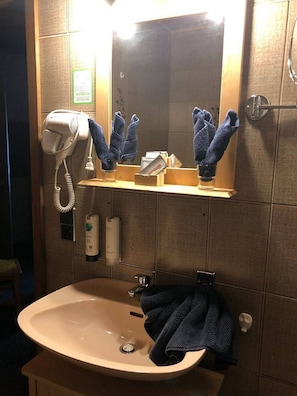 Bathroom features a sink, mirror, and hairdryer, with towels and hand soap nearby.