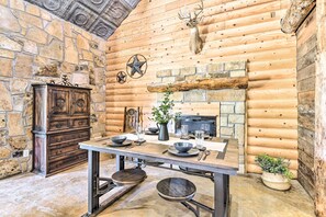 Una cucina rustica con pareti in pietra, tronchi di legno, un camino e un armadietto in legno.