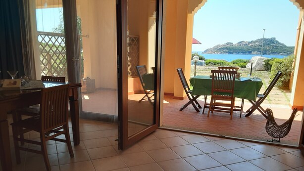Una habitación con puerta corrediza de vidrio que da a un patio exterior con mesa y sillas.