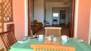 Un comedor con una mesa dispuesta para cuatro personas, un sofá y una cocina al fondo.