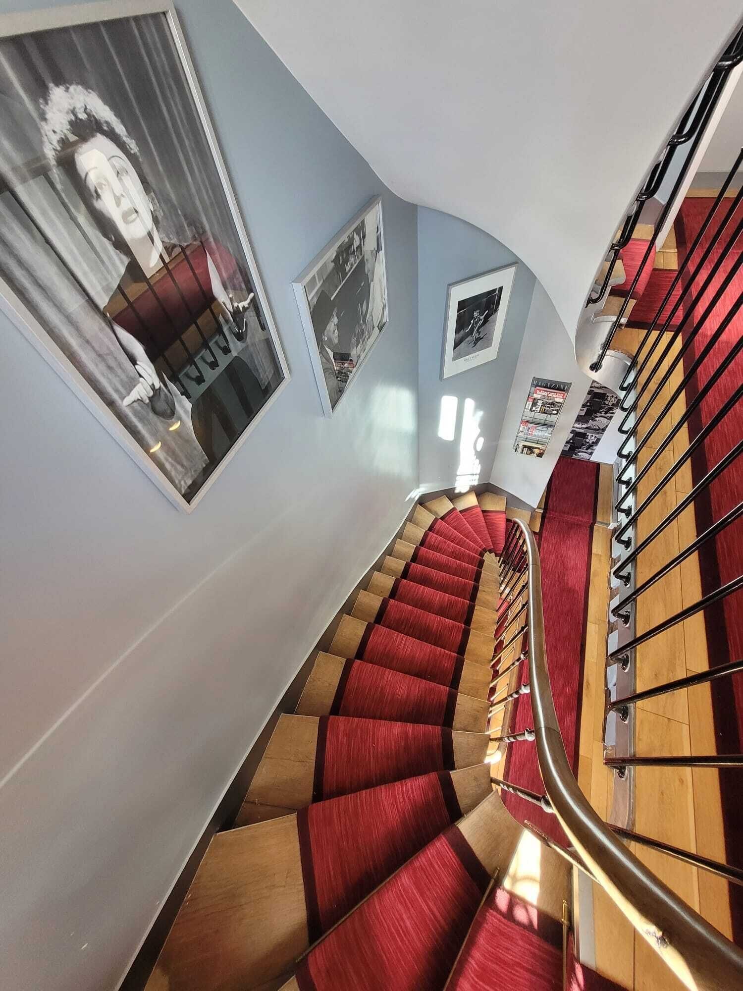 A spiral staircase with red carpeted steps and a metal railing.