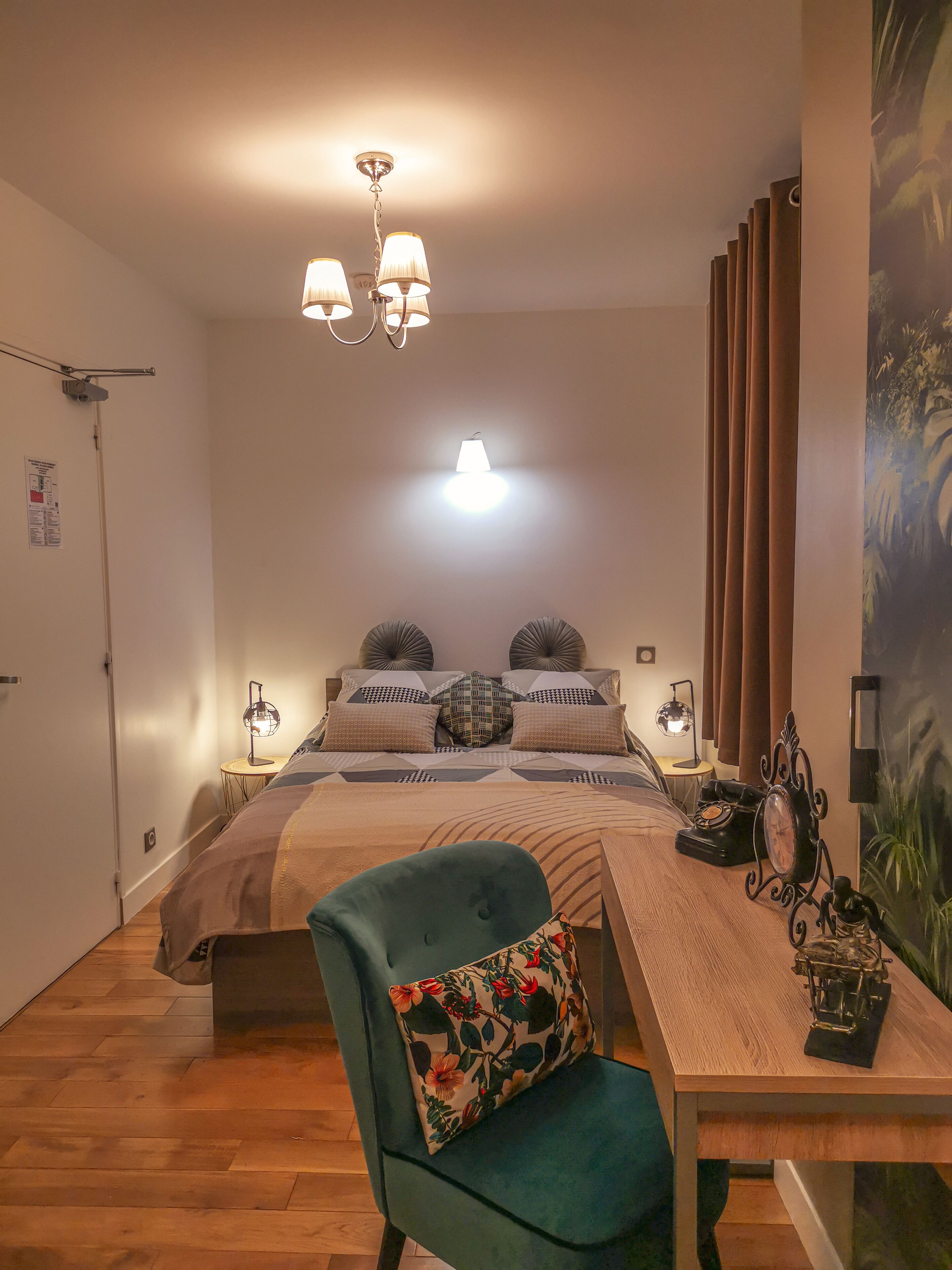 Un dormitorio con cama, escritorio, silla y lámpara de pared.