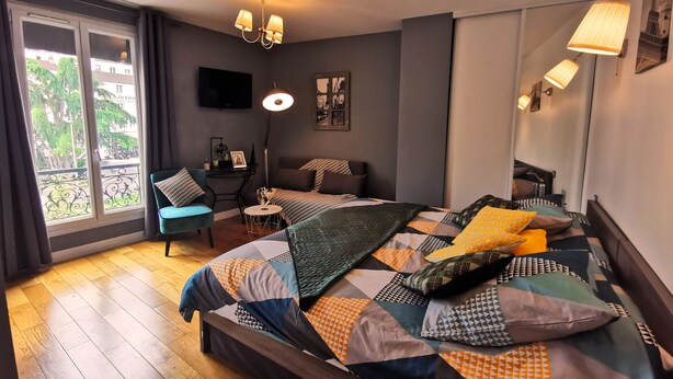 A bedroom with a large bed, a desk, a chair, and a balcony view. - Hôtel oh sèvres autrement (Sevres)