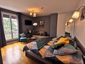 Quarto com uma cama grande, uma escrivaninha, uma cadeira e vista para uma varanda.