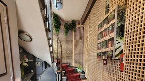 A staircase with red carpet, wooden walls with potted plants, and a visible door with a 'No Smoking' sign. - Hôtel oh sèvres autrement (Sevres)