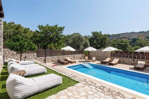 Relax by the serene pool surrounded by lush greenery and comfortable lounge seating.