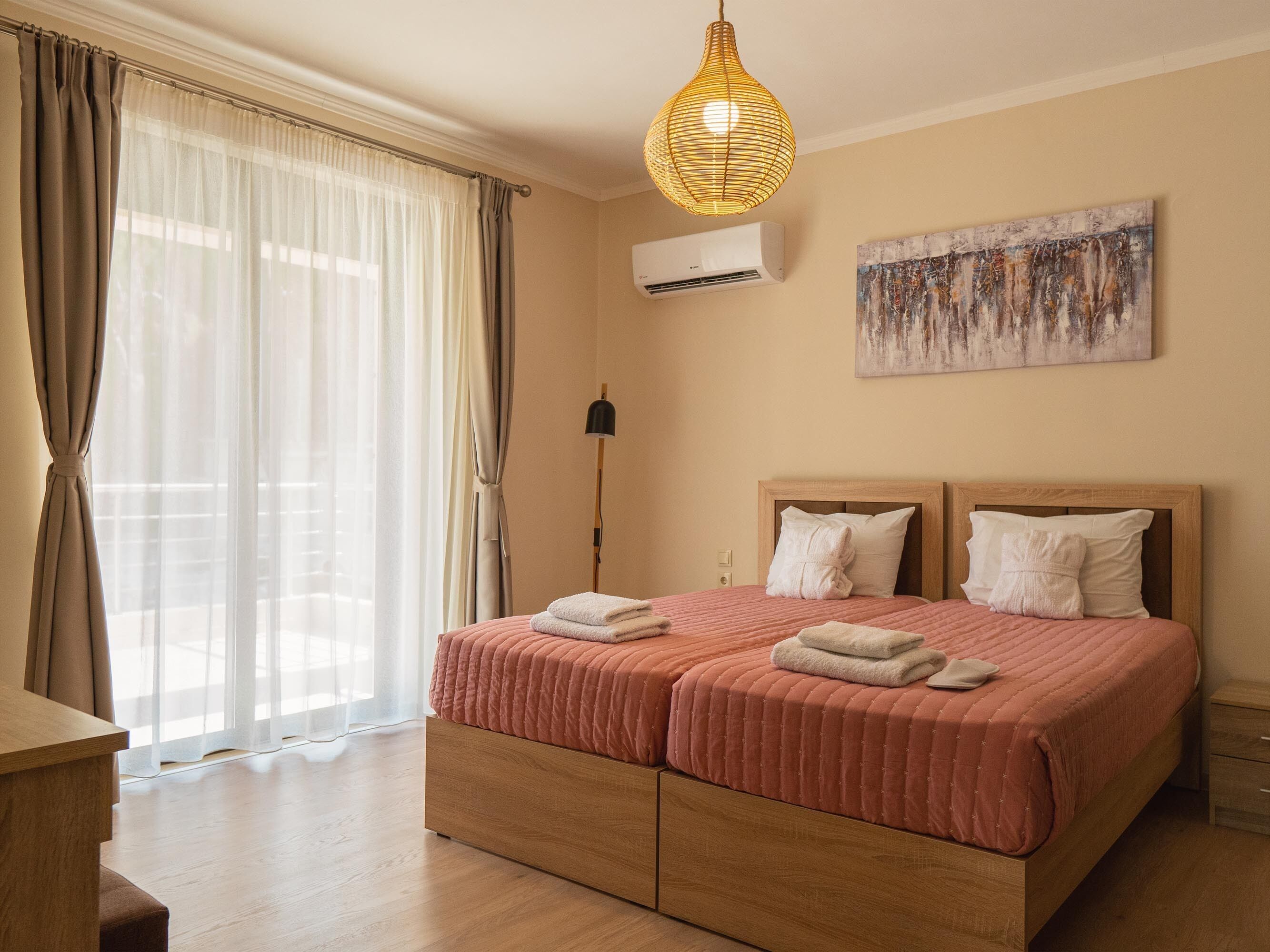 Une chambre d’hôtel avec un grand lit, un luminaire au plafond, un appareil de climatisation et un tableau au mur.