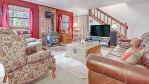 A cozy living room with a fireplace, a sofa, a television, and a staircase. - Cozy Creekside Cabin in La Veta: Hike & Fish! (La Veta)