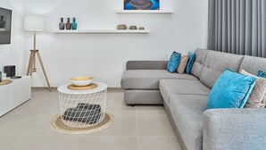 A modern living room with a grey sofa, a round coffee table, a floor lamp, and a painting on the wall.