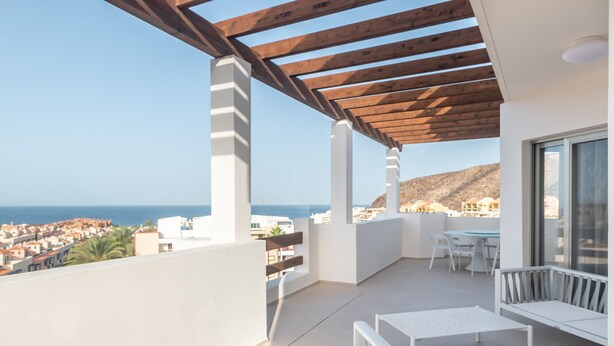 A balcony with a wooden pergola, white furniture, and a view of the sea and town. - Colinas - Tinerfe 3.4 DELUXE SEA VIEW & JACUZZI 3B (Arona)