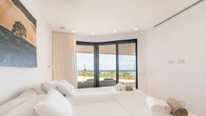 Une chambre d’hôtel avec un grand lit, une vue sur l’océan et un tableau au mur.