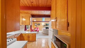 A kitchen with wooden cabinets, a white countertop, a microwave, and a gas stove. - Rocky Raccoon | Hot Tub, Lily Rock Views & Fireplace (Idyllwild)