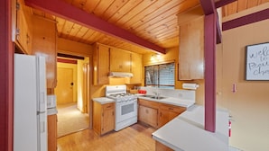 A compact kitchen with wooden cabinets, a white stove, and a sink. - Rocky Raccoon | Hot Tub, Lily Rock Views & Fireplace (Idyllwild)