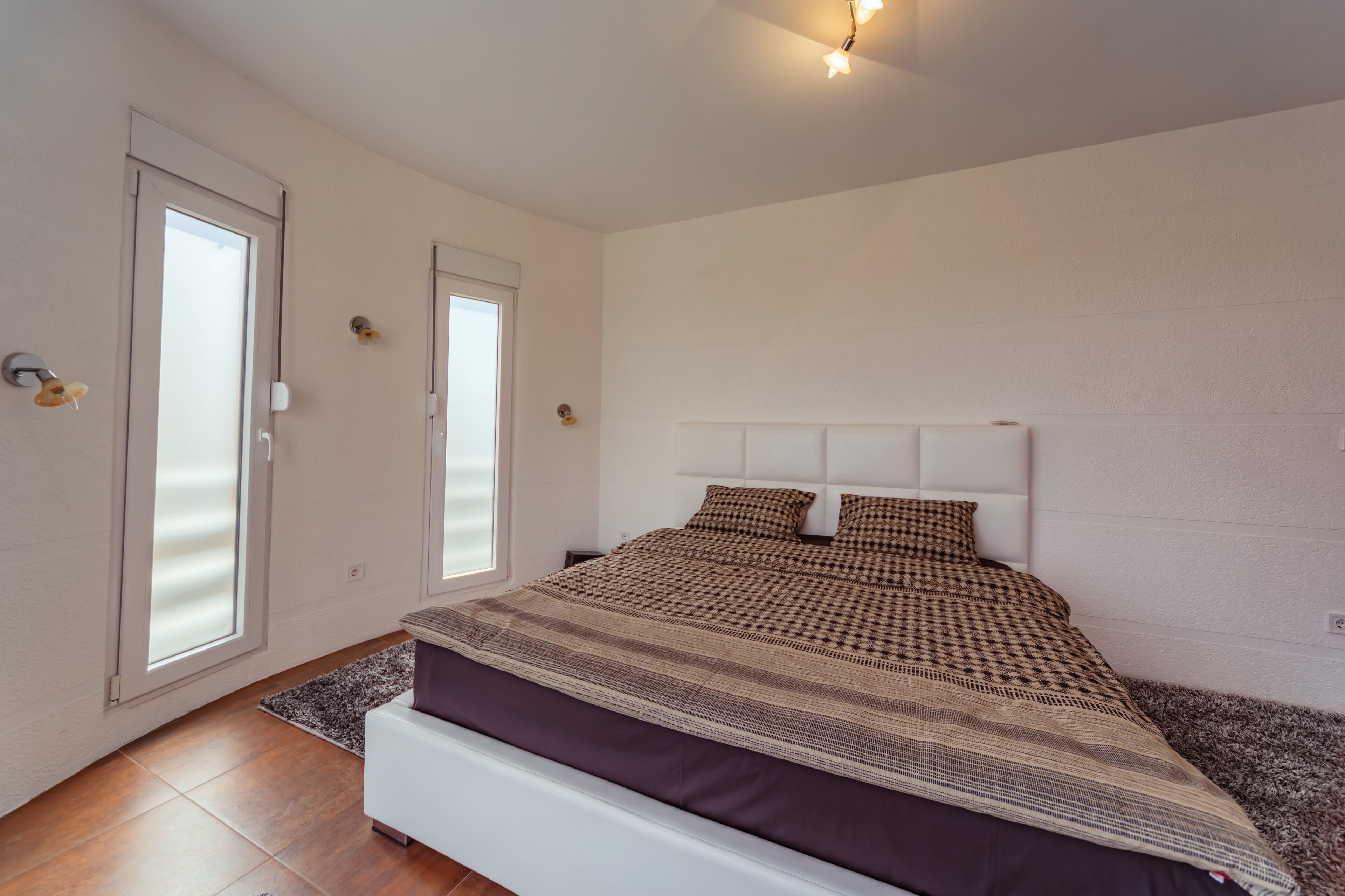 A bedroom with a bed, a window, and a door.