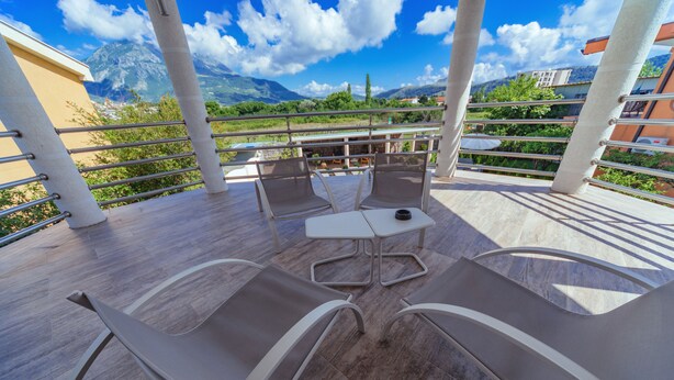 A terrace with two lounge chairs, a small table, and a view of mountains and greenery. - Second Floor (Бјелиши)
