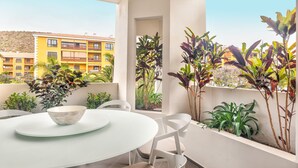 Un balcon avec une table ronde, des chaises et des plantes en pot.