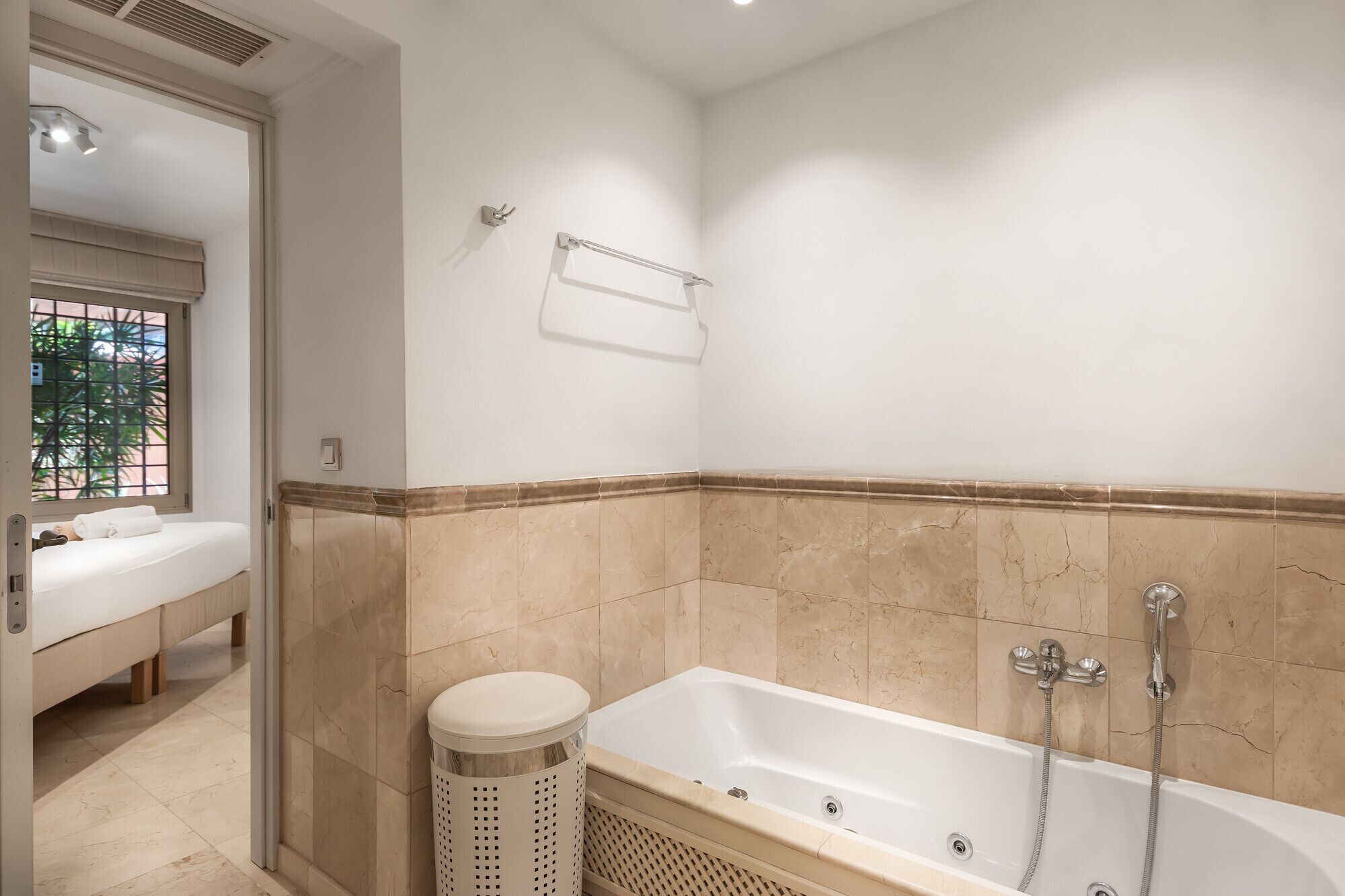 A bathroom with a bathtub, a toilet, and a window with a view of greenery.