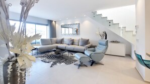 Ein modernes Wohnzimmer mit einer Eckcouch, einem Glastisch und einem Zebra-Teppich.