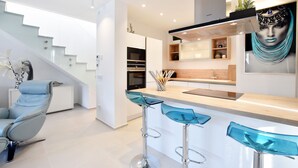 Eine moderne Küche mit einer zentralen Kochinsel, Barhocker und einer Treppe zu einer oberen Ebene.
