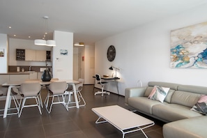 Un salon moderne comprenant un canapé, une table basse et un coin repas avec des chaises et une table.