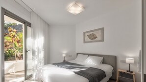 A modern bedroom with a large bed, a nightstand, a wall-mounted lamp, and a sliding glass door leading to a balcony. - Colinas -Bentor 0.3 POOL VIEW 1B  COLINAS (Arona)
