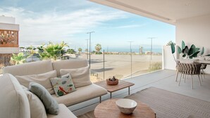 A modern living room with a sofa, a dining table, and a view of the beach. - Infinity 0.3 LUXE PARTIAL SEA VIEW 2B (Arona)