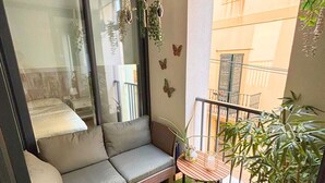 Un balcon avec un canapé gris, une petite table et des plantes en pot.