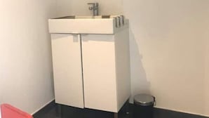 A bathroom with a white sink, mirror, and a trash bin. - Ty Lodge (Clohars-Fouesnant)