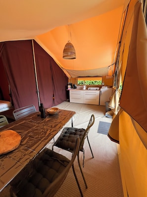 A compact kitchen with a dining area, a hanging light fixture, and a view through a window.