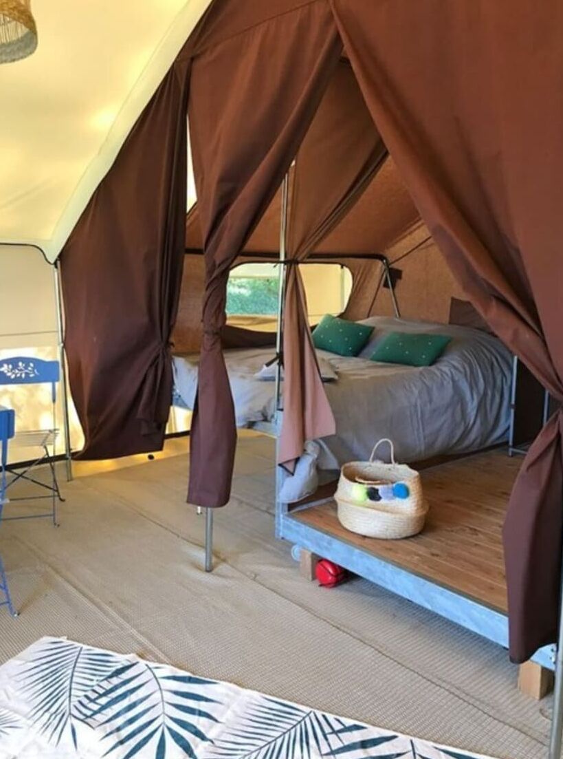 A tent with a bed, a small table, and a basket on the floor.