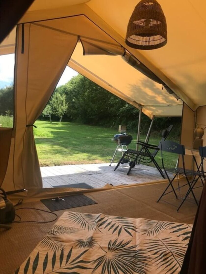 Et telt med udsigt over en græsplæne og en grill udenfor.
