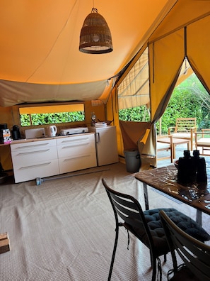 A tented accommodation with a kitchenette, dining area, and large windows.