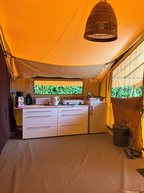 Une cuisine compacte dotée d’une grande fenêtre, d’un luminaire suspendu et d’une cuisinière portative.