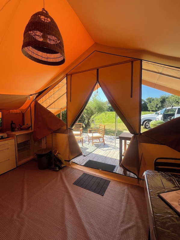 A tented accommodation with a kitchenette, seating area, and a view of the outdoors.
