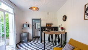 Une cuisine moderne avec un carrelage à motifs, un coin repas avec des tabourets et un canapé jaune.