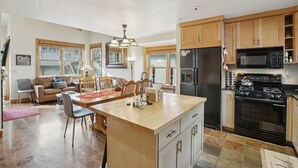 A spacious kitchen with wooden cabinets, a central island, and a dining area with a table and chairs. - Greyhawk Condos - Corner Unit - Private Hot Tub (Park City)