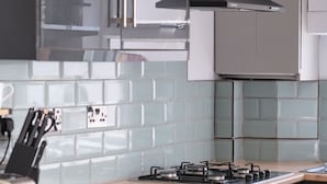 A modern kitchen with a gas stove, stainless steel appliances, and a wooden countertop.