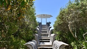 Un escalier menant à un espace de repos abrité, entouré d’une végétation luxuriante.