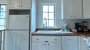 A compact kitchen with white cabinetry, a built-in refrigerator, a sink, and a coffee maker. - Across from Pool and Short Walk to Beach in Seaside, Fl + 2 Adult Bikes! (Santa Rosa Beach)