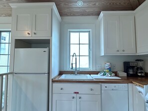 A compact kitchen with white cabinetry, a built-in refrigerator, a sink, and a coffee maker. - Across from Pool and Short Walk to Beach in Seaside, Fl + 2 Adult Bikes! (Santa Rosa Beach)