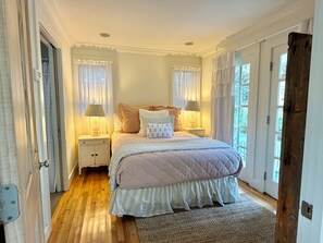 A bedroom with a bed, two bedside tables, a window, and a door. - Across from Pool and Short Walk to Beach in Seaside, Fl + 2 Adult Bikes! (Santa Rosa Beach)