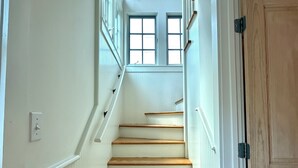 A staircase with wooden steps and white walls, leading to a room with a window. - Across from Pool and Short Walk to Beach in Seaside, Fl + 2 Adult Bikes! (Santa Rosa Beach)