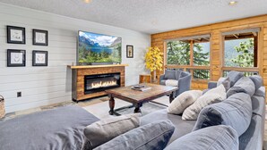 A cozy living room with a fireplace, a large TV, and a comfortable sofa. - Alpenglow Vacation Home At Windcliff 4 Bedroom Home by RedAwning (Estes Park)