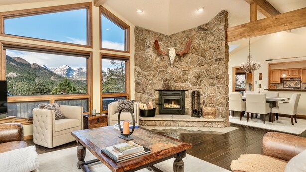 A spacious living room with a stone fireplace, large windows offering mountain views, and a cozy seating area. - Alpenglow Vacation Home At Windcliff 4 Bedroom Home by RedAwning (Estes Park)