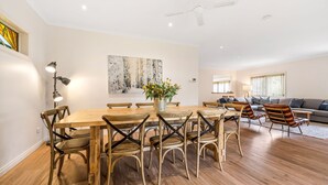 A spacious living area with a wooden dining table, chairs, a sofa, and a large painting on the wall. - The Parkers - in the Heart of Bright (Bright)
