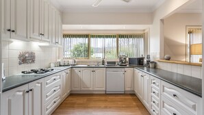 A modern kitchen with white cabinetry, a black countertop, and a view of greenery outside. - The Parkers - in the Heart of Bright (Bright)