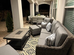 An outdoor patio area with wicker furniture, a table, and a grill.